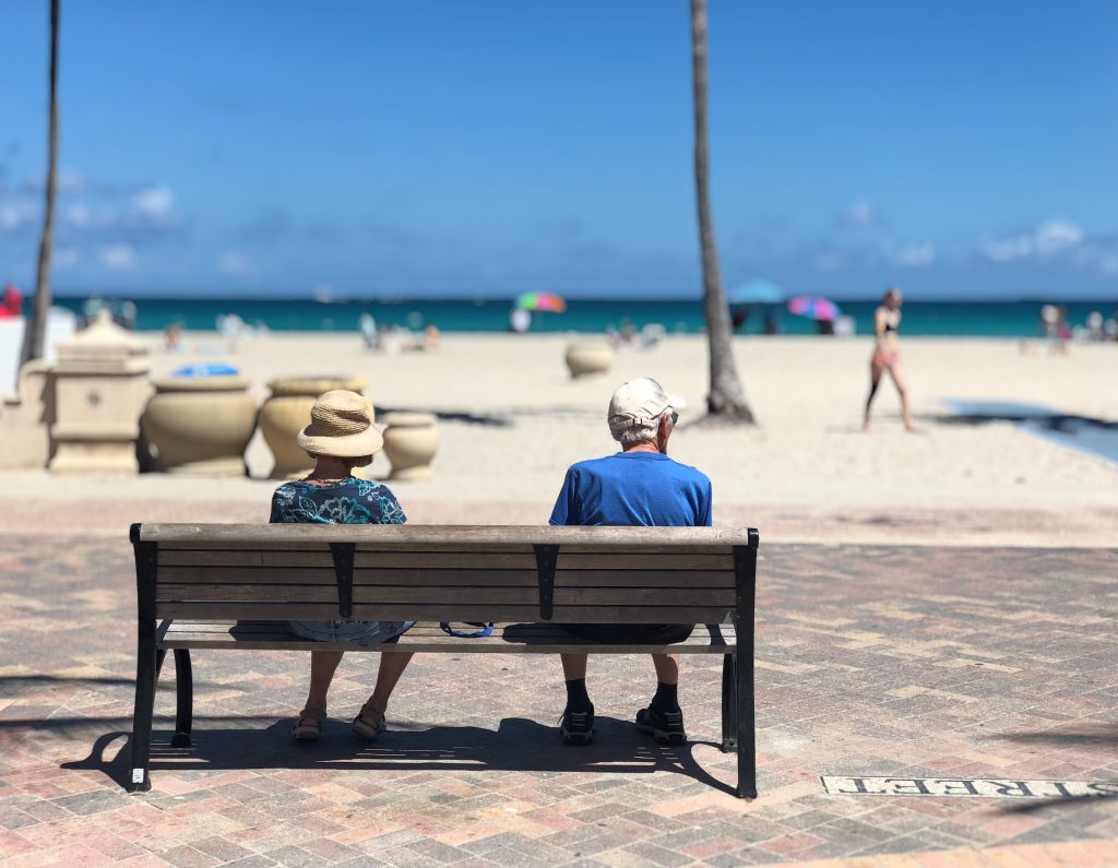 Ancianos en un banco frente a la playa.