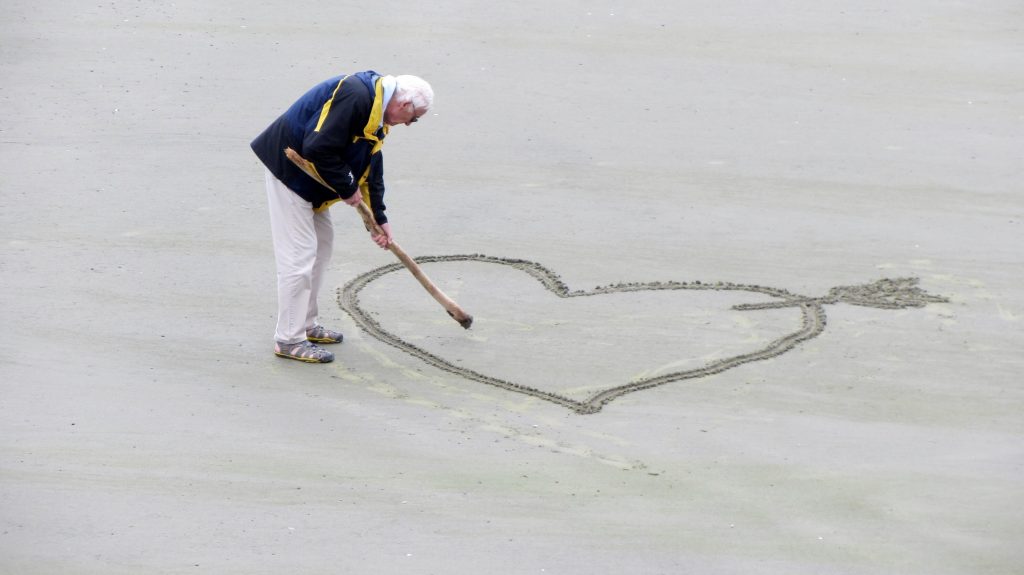 Un pensionista dibuja un corazón en la arena
