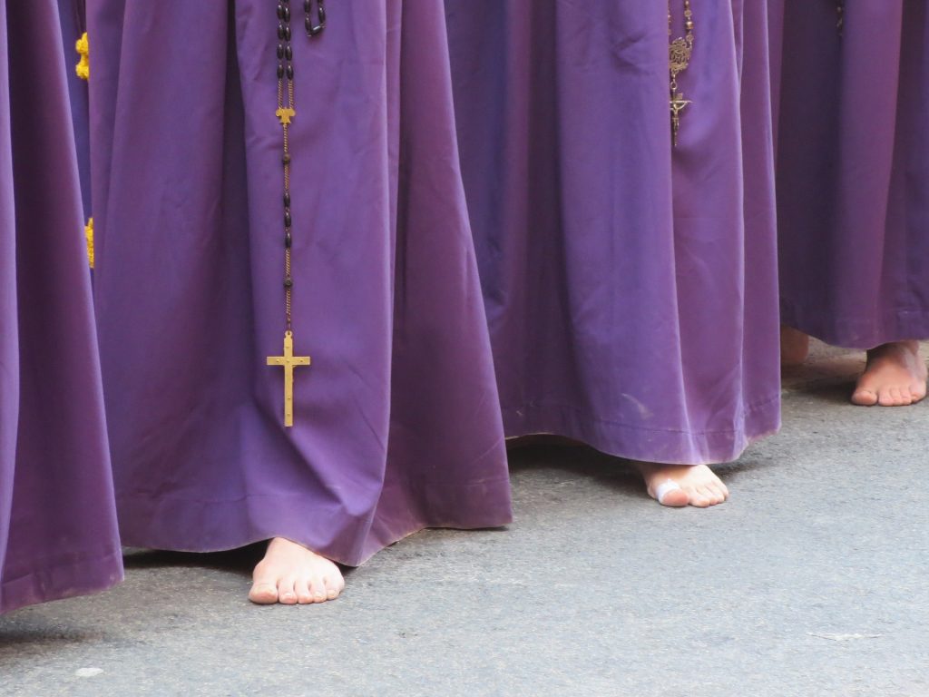 Blootsvoetse mannen in gewaden in een processie tijdens Pasen in Spanje.